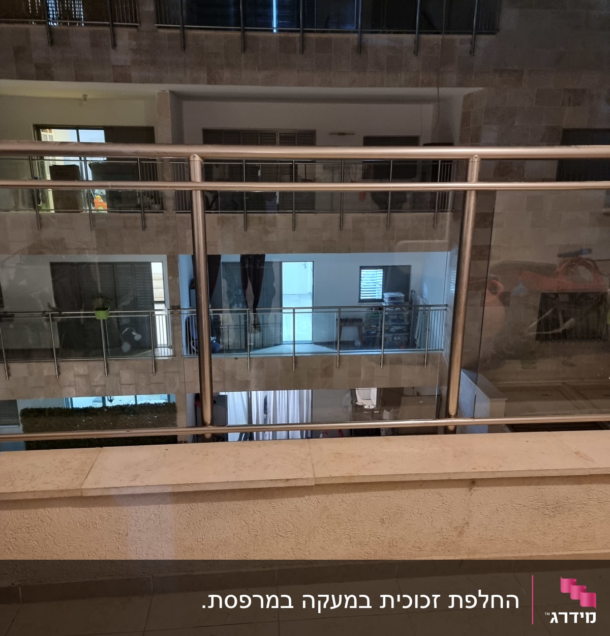 מעקה זכוכית עם מסגרת מתכת במרפסת בניין